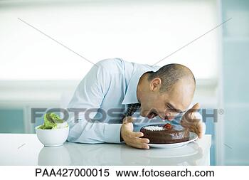 Stock Image - man sitting at 
table with chocolate 
cake and bowl 
of lettuce. fotosearch 
- search stock 
photos, pictures, 
images, and photo 
clipart