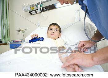 Stock Photo - boy lying in hospital 
bed holding toy 
car while intern 
checks pulse. 
fotosearch - search 
stock photos, 
pictures, images, 
and photo clipart