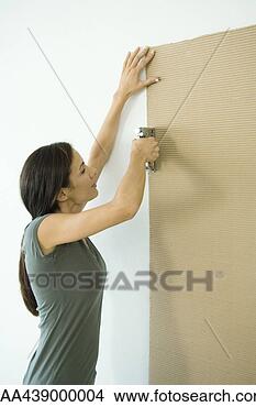 Stock Photo - woman stapling 
sheet of cardboard 
to wall. fotosearch 
- search stock 
photos, pictures, 
images, and photo 
clipart