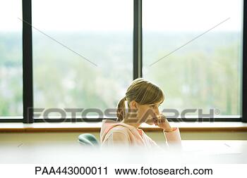 Stock Photography - female college 
student sitting 
in front of window, 
biting finger. 
fotosearch - search 
stock photos, 
pictures, images, 
and photo clipart