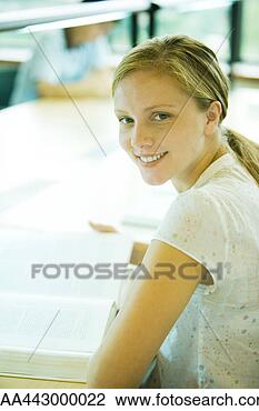 Stock Photo - female college 
student sitting 
at table in library, 
smiling at camera. 
fotosearch - search 
stock photos, 
pictures, images, 
and photo clipart