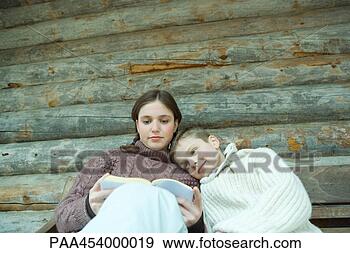 Stock Photograph - teenage girl reading 
book, little brother 
resting head on 
her shoulder. 
fotosearch - search 
stock photos, 
pictures, images, 
and photo clipart