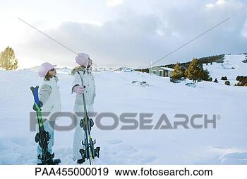 Stock Photograph - two young friends 
standing together, 
holding skis, 
looking away. 
fotosearch - search 
stock photos, 
pictures, images, 
and photo clipart