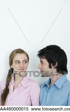 Stock Image - young couple smirking 
at each other, 
head and shoulders, 
portrait. fotosearch 
- search stock 
photos, pictures, 
images, and photo 
clipart