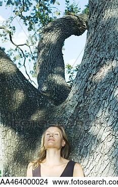 Stock Photo - blonde woman leaning 
against tree, 
eyes closed, low 
angle view. fotosearch 
- search stock 
photos, pictures, 
images, and photo 
clipart