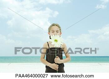 Picture - girl holding up 
flower, eyes closed, 
standing on beach, 
waist up. fotosearch 
- search stock 
photos, pictures, 
images, and photo 
clipart