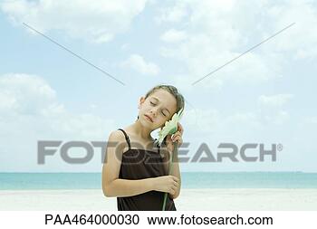 Stock Photography - girl standing 
on beach,  holding 
flower close to 
ear,  eyes closed. 
fotosearch - search 
stock photos, 
pictures, images, 
and photo clipart