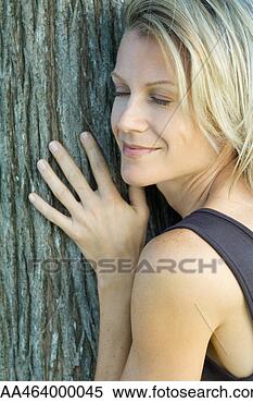 Stock Image - woman leaning 
against tree trunk, 
 eyes closed, 
 smiling,  cropped. 
fotosearch - search 
stock photos, 
pictures, images, 
and photo clipart
