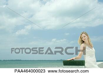 Stock Photo - woman sitting 
near sea, touching 
blades of wheat 
grass. fotosearch 
- search stock 
photos, pictures, 
images, and photo 
clipart
