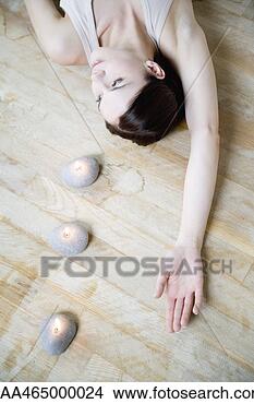 Stock Photo - woman lying on 
the ground with 
candles, arm raised, 
looking away. 
fotosearch - search 
stock photos, 
pictures, images, 
and photo clipart