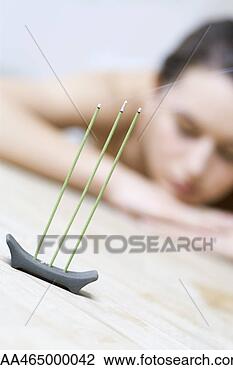 Stock Photo - woman reclining, 
 head resting 
on arms,  focus 
on incense burning 
in. fotosearch 
- search stock 
photos, pictures, 
images, and photo 
clipart