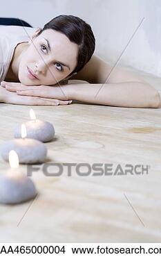Stock Photo - young woman lying 
on stomach,  head 
resting on arms, 
 burning candles. 
fotosearch - search 
stock photos, 
pictures, images, 
and photo clipart