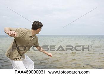 Stock Photography - man poised to 
skim stone on 
surface of ocean, 
 side view,  three. 
fotosearch - search 
stock photos, 
pictures, images, 
and photo clipart