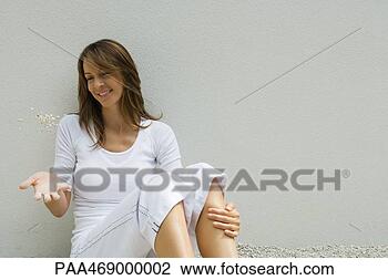 Stock Photo - woman sitting 
on ground with 
knees up,  tossing 
handful of gravel. 
fotosearch - search 
stock photos, 
pictures, images, 
and photo clipart