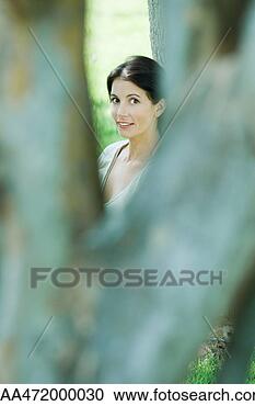 Stock Photography - woman looking 
between tree branches, 
smiling at camera. 
fotosearch - search 
stock photos, 
pictures, images, 
and photo clipart