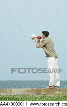 Stock Photography - man using megaphone, 
facing ocean horizon, 
full length. fotosearch 
- search stock 
photos, pictures, 
images, and photo 
clipart