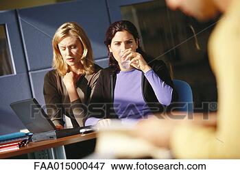 Picture - two female office 
workers using 
laptop, one drinking 
glass of water. 
fotosearch - search 
stock photos, 
pictures, images, 
and photo clipart