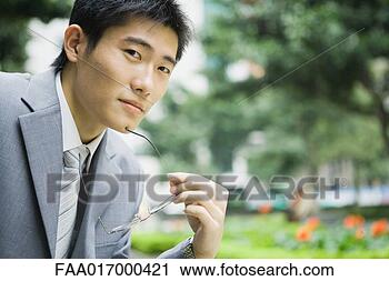Stock Photography - businessman holding 
glasses, looking 
at camera, portrait. 
fotosearch - search 
stock photos, 
pictures, images, 
and photo clipart