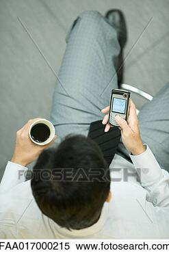 Stock Image - businessman using 
smart phone, holding 
cup of coffee. 
fotosearch - search 
stock photos, 
pictures, images, 
and photo clipart
