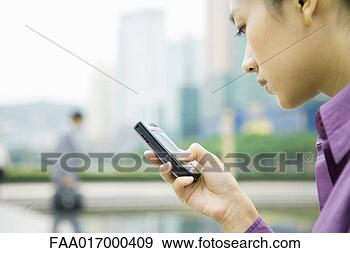 Stock Photograph - businesswoman 
using messaging 
phone, close-up, 
side view. fotosearch 
- search stock 
photos, pictures, 
images, and photo 
clipart