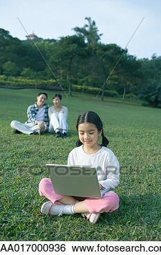 Stock Photo - girl sitting in 
grass using laptop, 
parents sitting 
in background. 
fotosearch - search 
stock photos, 
pictures, images, 
and photo clipart