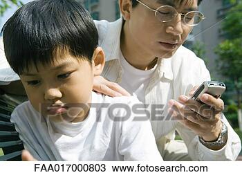 Stock Photo - man looking at 
cell phone while 
son looks away, 
frowning. fotosearch 
- search stock 
photos, pictures, 
images, and photo 
clipart