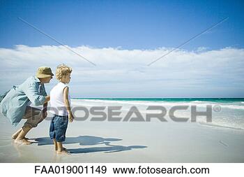 Stock Photograph - woman and boy 
standing on beach, 
looking towards 
waves. fotosearch 
- search stock 
photos, pictures, 
images, and photo 
clipart