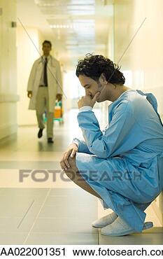 Stock Photography - male patient crouching 
in hospital corridor, 
 holding head, 
 looking. fotosearch 
- search stock 
photos, pictures, 
images, and photo 
clipart