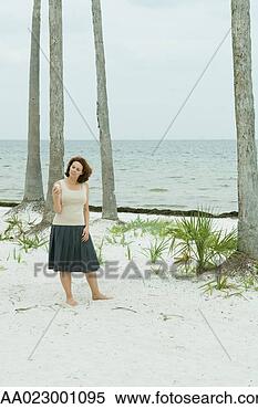 Stock Image - woman standing 
on the beach looking 
at cell phone, 
head tilted. fotosearch 
- search stock 
photos, pictures, 
images, and photo 
clipart