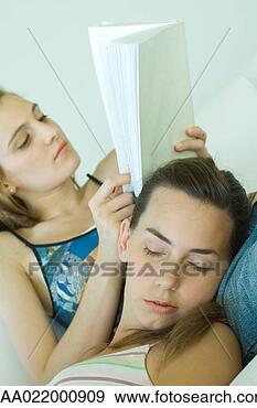Stock Photograph - young woman reading 
book,  friend 
resting head on 
her lap with eyes. 
fotosearch - search 
stock photos, 
pictures, images, 
and photo clipart