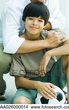 Stock Photo - boy crouching 
in front of father, 
 holding soccer 
ball,  smiling 
at. fotosearch 
- search stock 
photos, pictures, 
images, and photo 
clipart