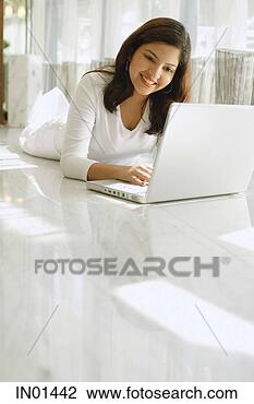 Stock Photo - woman dressed 
in white, lying 
on white floor, 
using laptop. 
fotosearch - search 
stock photos, 
pictures, images, 
and photo clipart