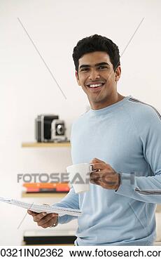Stock Photo - young man with 
coffee and paper 
smiling at camera. 
fotosearch - search 
stock photos, 
pictures, images, 
and photo clipart