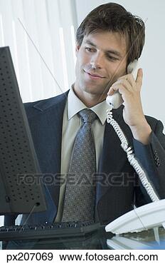 Stock Photograph - businessman at 
computer using 
telephone. fotosearch 
- search stock 
photos, pictures, 
images, and photo 
clipart