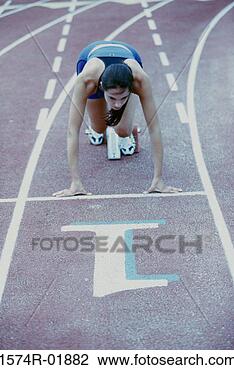 Stock Photo - high angle view 
of a young woman 
at the starting 
position of a. 
fotosearch - search 
stock photos, 
pictures, images, 
and photo clipart