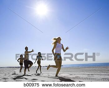 Stock Image - low angle view 
of four young 
people running 
on the beach. 
fotosearch - search 
stock photos, 
pictures, images, 
and photo clipart