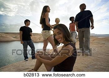 Stock Photo - portrait of a 
young woman sitting 
on a rock with 
friends in the. 
fotosearch - search 
stock photos, 
pictures, images, 
and photo clipart