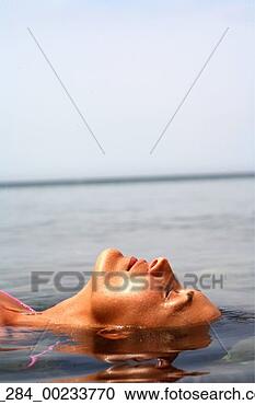 Stock Photography - side view head 
shot woman floating 
on water with 
eyes closed. fotosearch 
- search stock 
photos, pictures, 
images, and photo 
clipart