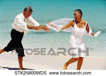 Stock Photo - side profile of 
a mature couple 
running playfully 
on the beach. 
fotosearch - search 
stock photos, 
pictures, images, 
and photo clipart