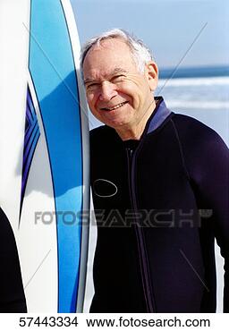Stock Photo - portrait of an 
elderly man holding 
an upright surfboard. 
fotosearch - search 
stock photos, 
pictures, images, 
and photo clipart