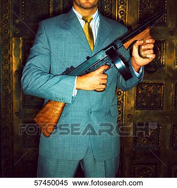Stock Image - view of a man 
with face hidden 
standing holding 
a machine gun. 
fotosearch - search 
stock photos, 
pictures, images, 
and photo clipart