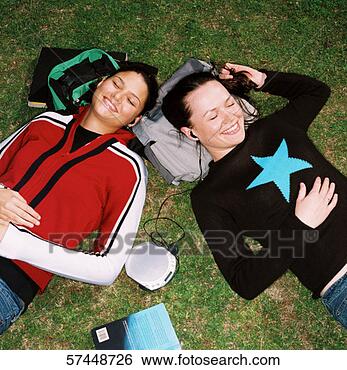 Stock Photo - two teenage girls 
lying on the grass 
listening to earphones 
smiling. fotosearch 
- search stock 
photos, pictures, 
images, and photo 
clipart