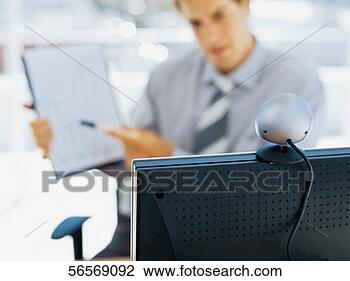 Stock Photo - businessman sitting 
in front of a 
video conference 
camera in an office. 
fotosearch - search 
stock photos, 
pictures, images, 
and photo clipart