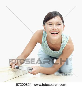 Stock Photo - young woman smiling 
and hammering 
a nail into a 
wooden wall border. 
fotosearch - search 
stock photos, 
pictures, images, 
and photo clipart