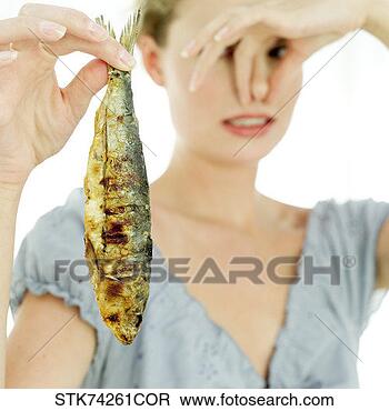 Stock Photo - close-up of woman 
holding a fried 
fish and holding 
her nose. fotosearch 
- search stock 
photos, pictures, 
images, and photo 
clipart