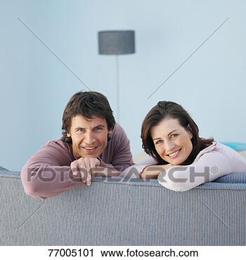 Stock Photography - couple sitting 
on sofa, turning 
around, portrait. 
fotosearch - search 
stock photos, 
pictures, images, 
and photo clipart