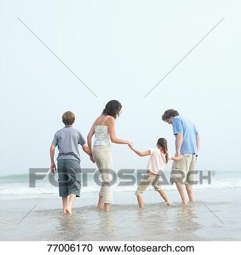 Stock Photography - family with two 
kids (9-12) standing 
ankle deep in 
water on beach. 
fotosearch - search 
stock photos, 
pictures, images, 
and photo clipart