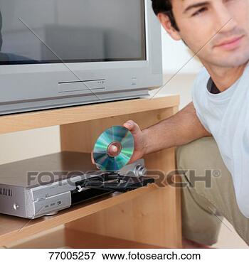 Picture - man loading dvd 
into dvd player. 
fotosearch - search 
stock photos, 
pictures, images, 
and photo clipart