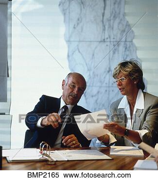 Stock Image - mature male executive 
and woman executive 
reviewing papers 
over table. fotosearch 
- search stock 
photos, pictures, 
images, and photo 
clipart