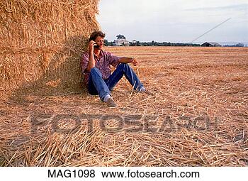 Stock Photo - young farmer with 
cellular flip-phone 
sitting on straw 
bales. fotosearch 
- search stock 
photos, pictures, 
images, and photo 
clipart